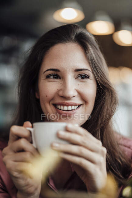 Glückliche erwachsene Geschäftsfrau mit Kaffee, während sie im Café wegschaut — Stockfoto
