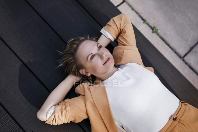 Relaxed donna d'affari matura con le mani dietro la testa sdraiato sul pavimento — Foto stock