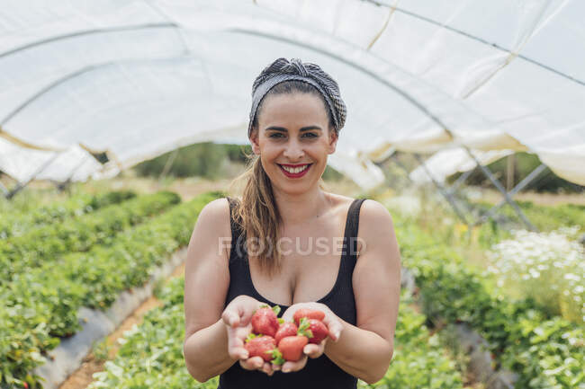 Bonita agricultora feliz segurando morangos frescos na fazenda orgânica — Fotografia de Stock