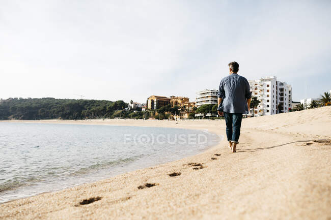 Uomo che cammina sulla spiaggia durante la giornata di sole — Foto stock
