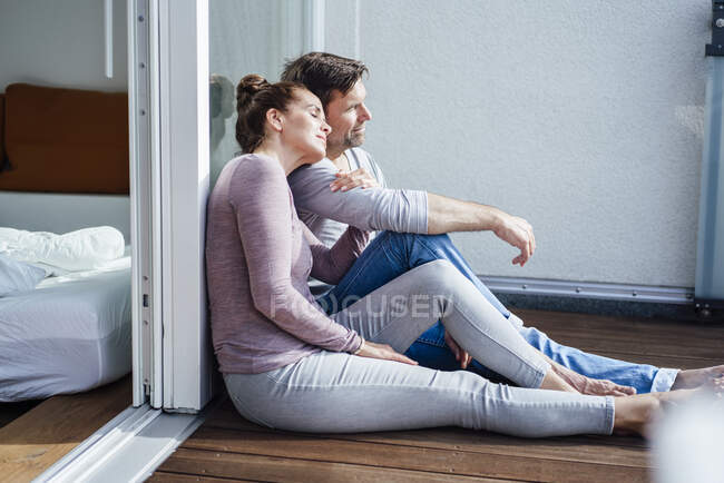 Coppia matura seduta in balcone appoggiata su vetro durante la giornata di sole — Foto stock