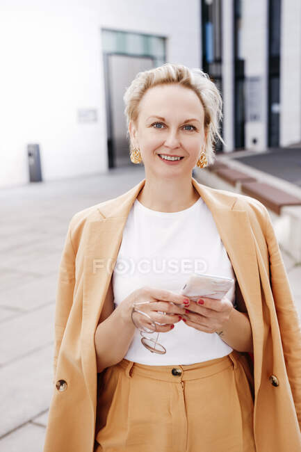 Sonriente hermosa mujer de negocios con teléfono inteligente - foto de stock