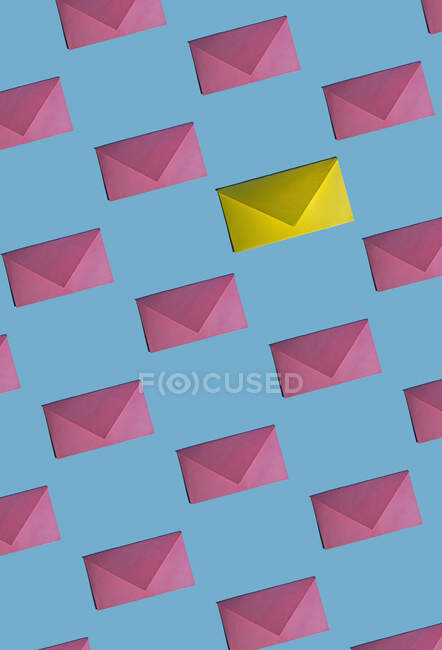 Patrón de filas de sobres rosados con uno solo amarillo - foto de stock
