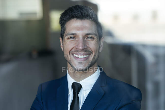Hombre de negocios seguro sonriendo mientras está de pie en el cargo - foto de stock