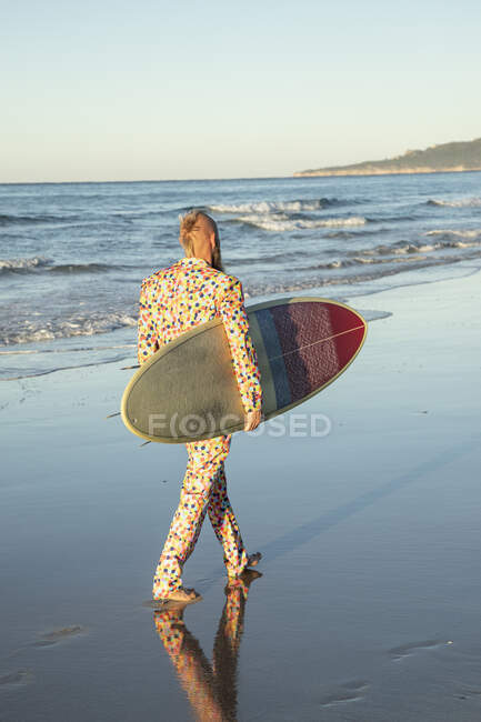 Чоловік у костюмі з серфінгом під час прогулянки на пляжі. — стокове фото