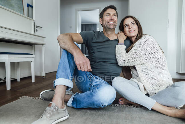Дорослий чоловік і дружина мріють, сидячи вдома на підлозі. — стокове фото