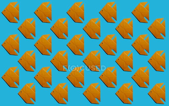 Pattern of orange origami fish against blue background — Stock Photo