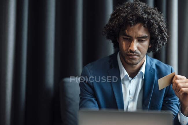Giovane uomo d'affari fiducioso che utilizza il computer portatile mentre detiene la carta di credito in ufficio — Foto stock
