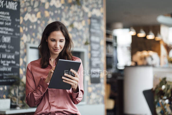 Femme indépendante souriante travaillant sur tablette numérique dans un café — Photo de stock