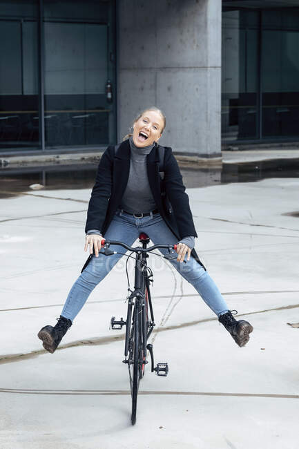 Donna allegra che fa ciclismo su strada contro la struttura — Foto stock