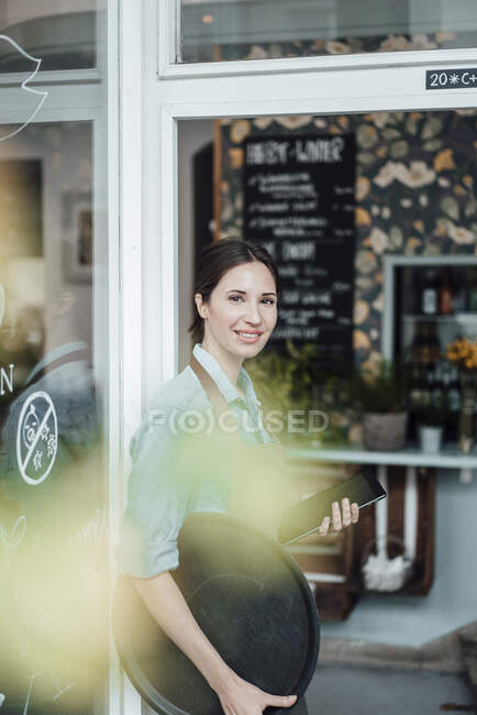 Female manager with digital tablet and tray outside cafe — Stock Photo