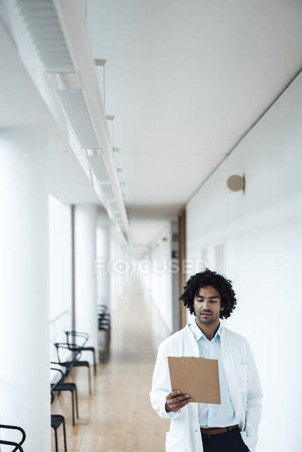 Jovem médico confiante olhando para a área de transferência no corredor do hospital — Fotografia de Stock