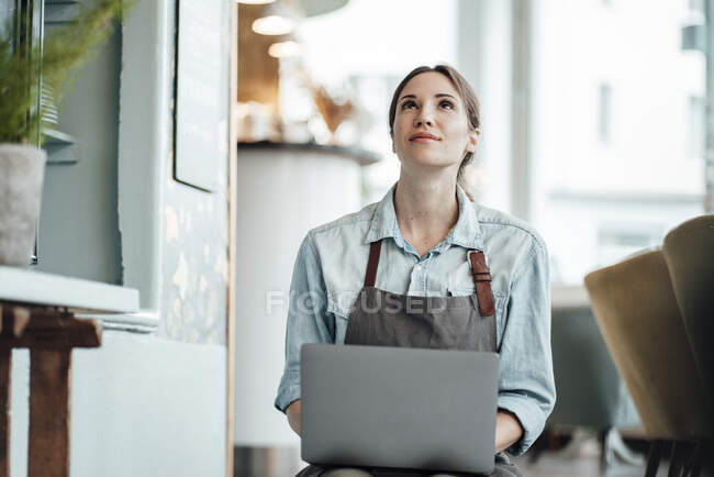 Жінка-підприємець з ноутбуком, який дивиться в кав'ярню — стокове фото