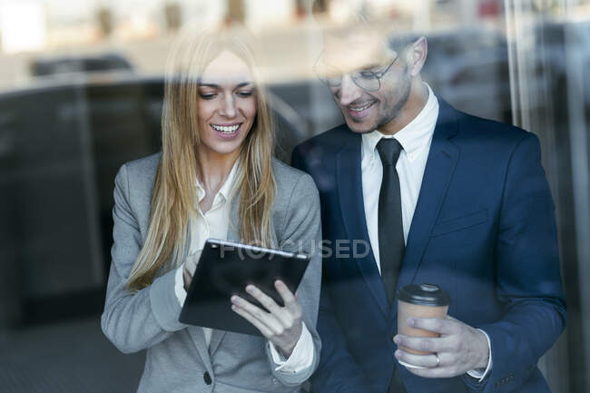 Усміхнена бізнесменка, яка працює над цифровим планшетом з колегою під час роботи. — стокове фото