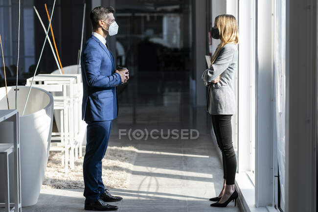 Бізнесмени, одягнені в захисну маску, стоять на соціальній відстані під час роботи в офісі під час COVID-19 — стокове фото