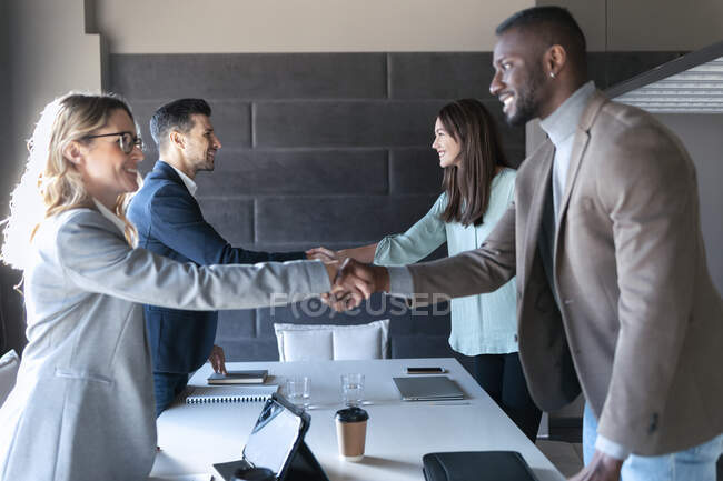 Деловые люди пожимают руки, стоя в комнате для совещаний в офисе — стоковое фото