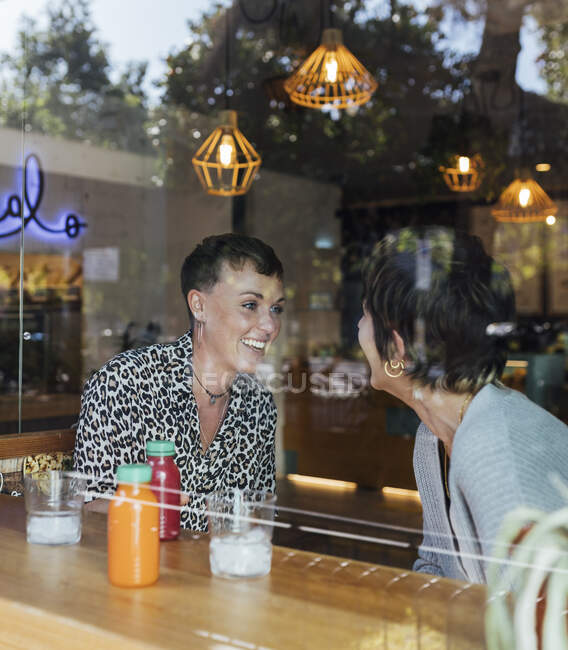 Smiling friends talking while sitting at restaurant — Stock Photo