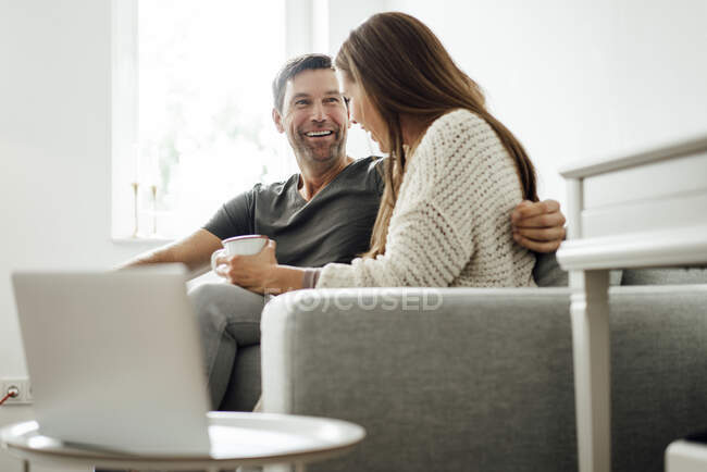 Allegro coppia matura ridendo mentre seduto sul divano a casa — Foto stock