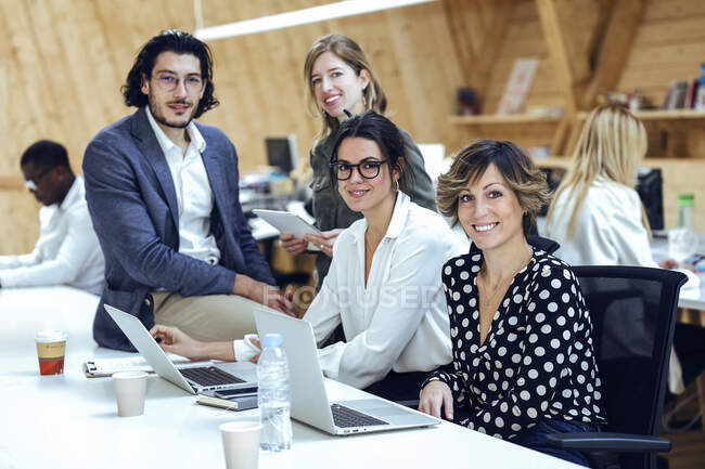 Business team sorridente con laptop che crea idee creative alla scrivania in un luogo di coworking — Foto stock