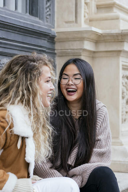 Amigos do sexo feminino rindo enquanto sentado ao ar livre — Fotografia de Stock