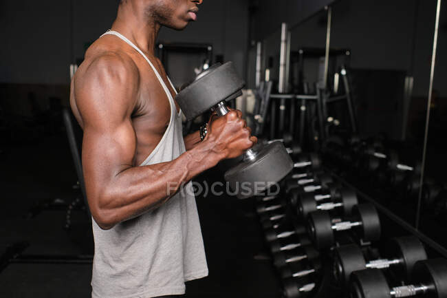 Athletic young male exercising with dumbbells at gym — Stock Photo