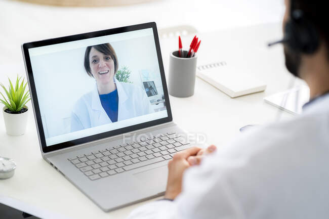 Male doctor discussing with female colleague on video conference through laptop — Stock Photo