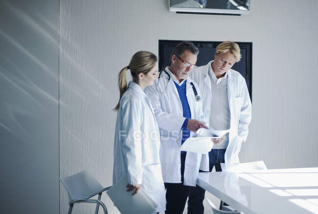 Médecin chevronné évaluant la paperasserie des collègues à l'hôpital — Photo de stock