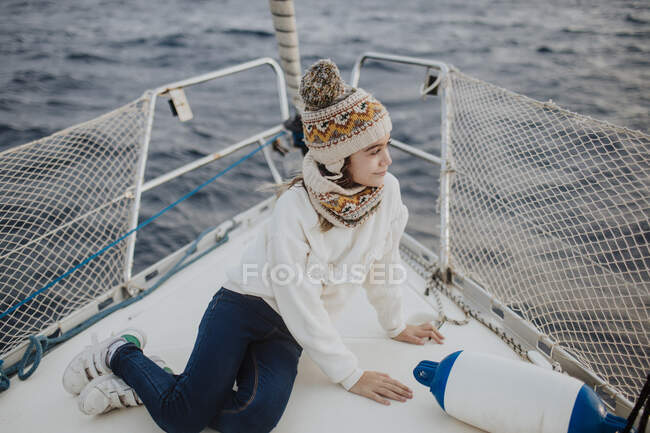 Ragazza carina con cappello a maglia seduto sulla barca a vela durante le vacanze — Foto stock