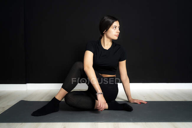 Молодая спортсменка сидит в позе сапожника на коврике для упражнений в студии йоги — стоковое фото