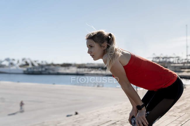Nachdenkliche Joggerin ruht sich auf Pier aus — Stockfoto