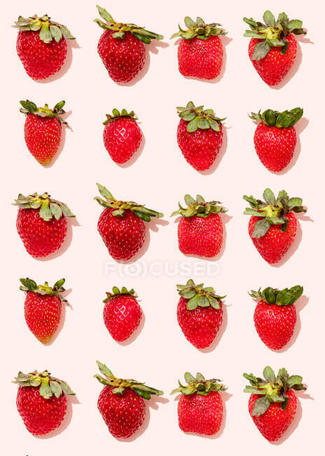 Pattern of fresh ripe strawberries lying against light pink background — Stock Photo