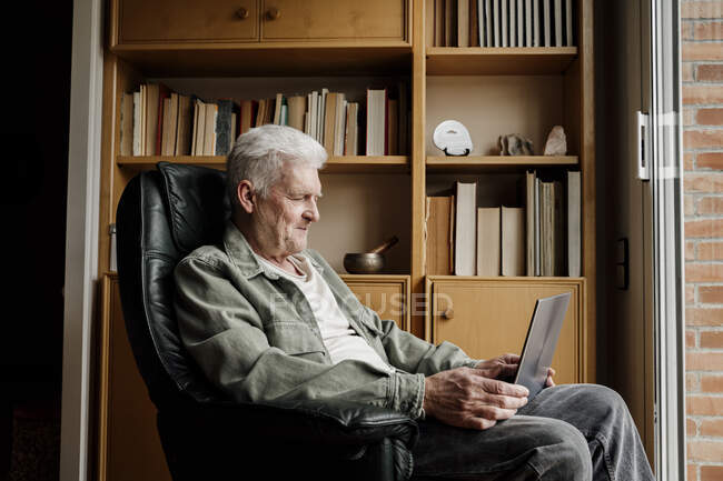 Uomo anziano che utilizza il computer portatile a casa — Foto stock