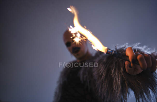 Homem segurando fogo de artifício contra fundo cinza — Fotografia de Stock