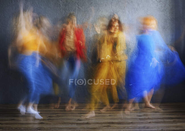 Donne in abito multicolore che ballano sul pavimento in studio — Foto stock