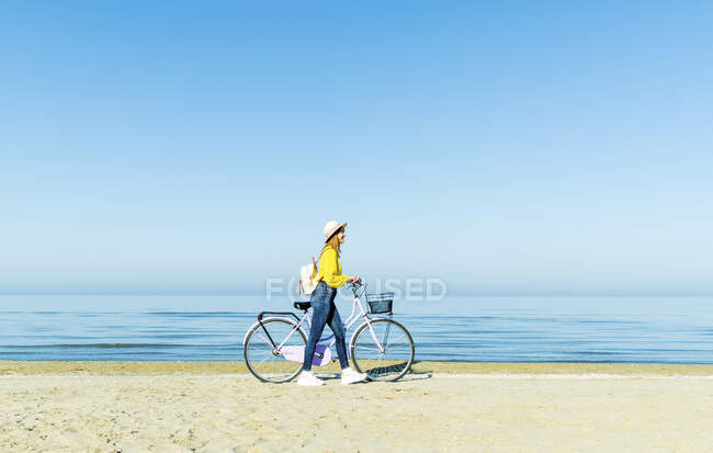 Frau läuft mit Fahrrad am Strand — Stockfoto