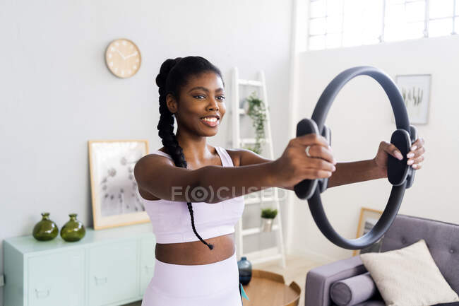 Smiling woman exercising with pilates ring at home — Stock Photo