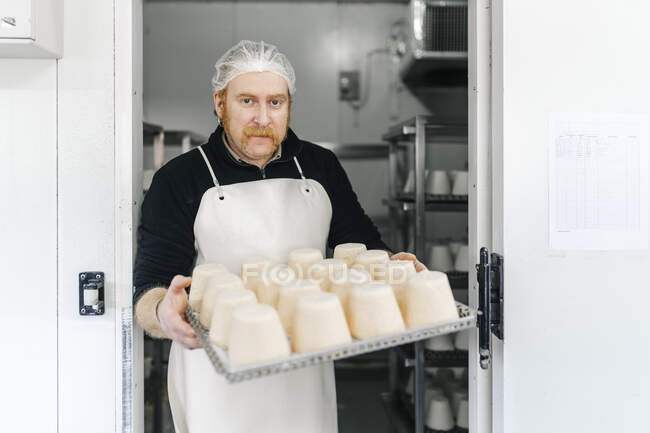Maturo maschio chef tenendo vassoio formaggio mentre in piedi a porta in fabbrica — Foto stock