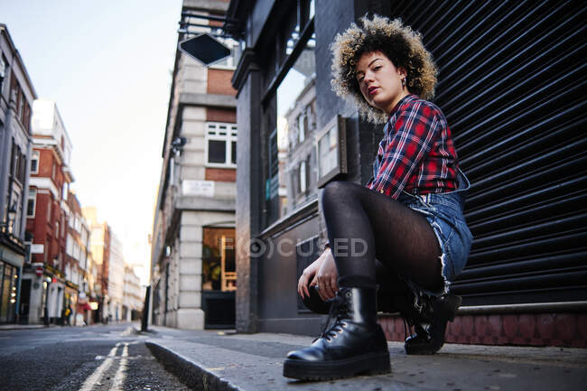 Jeune femme accroupie sur le sentier de la ville — Photo de stock