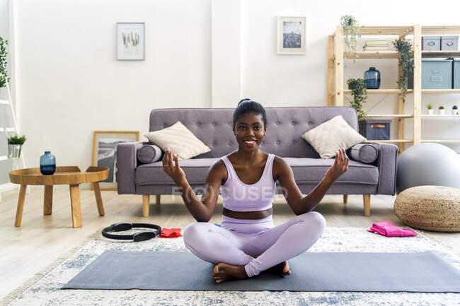 Sorridente giovane donna che pratica yoga a casa — Foto stock