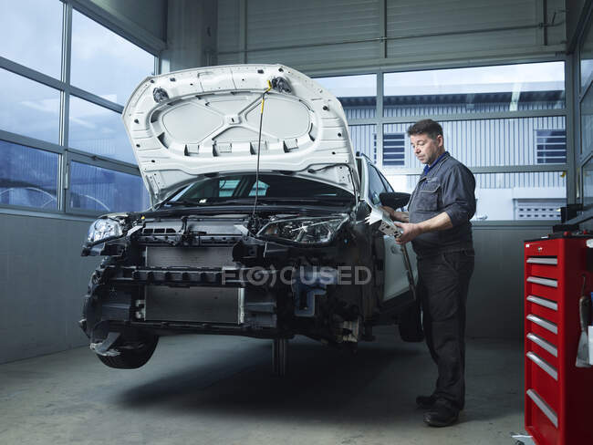 Maduro especialista instalar peças de carro na oficina de reparação de automóveis — Fotografia de Stock