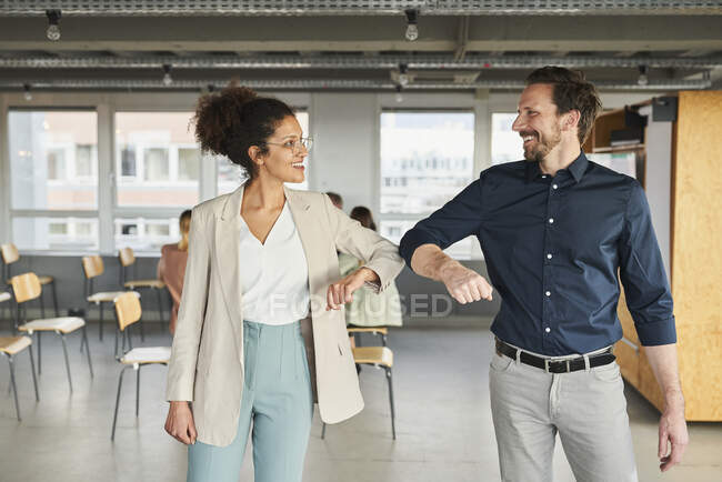 Entrepreneurs hommes et femmes souriant tout en saluant avec des bosses de coude dans la salle de conseil — Photo de stock