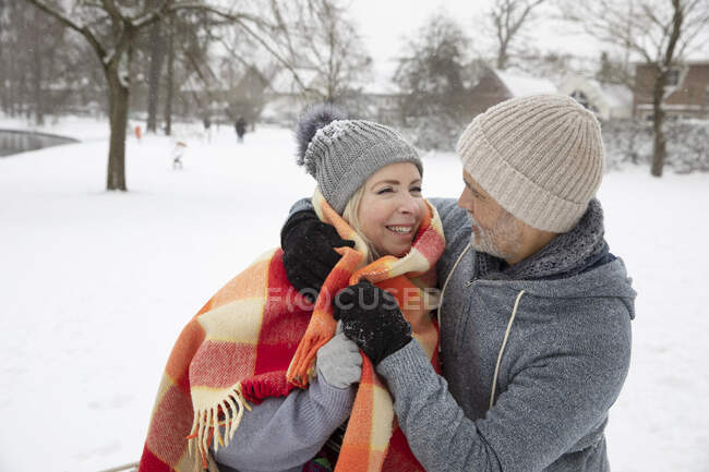 Uomo avvolgente donna con coperta durante l'inverno — Foto stock