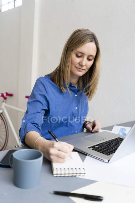 Femme d'affaires écrivant tout en travaillant dans le bureau — Photo de stock