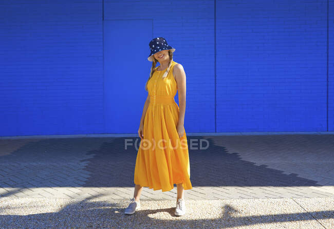 Femme mûre portant un chapeau seau debout devant le mur par une journée ensoleillée — Photo de stock
