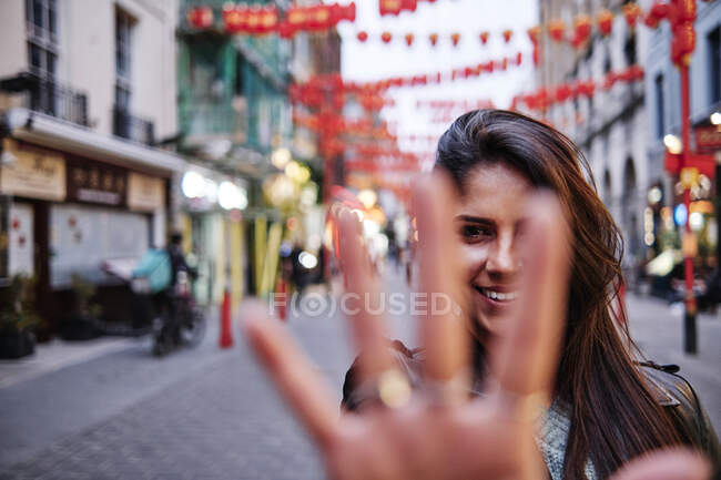 Усміхнена жінка показує долоню, стоячи на вулиці в місті — стокове фото