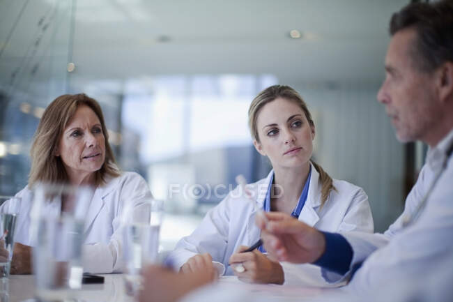 Female doctors looking at male healthcare worker explaining during meeting in hospital — Stock Photo