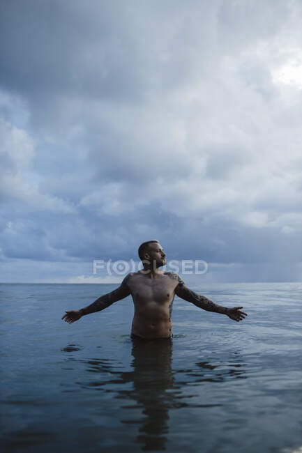 Mann schaut weg, während er im Meer steht — Stockfoto