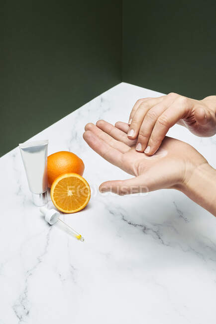 Woman applying moisturizer over marble table — Stock Photo