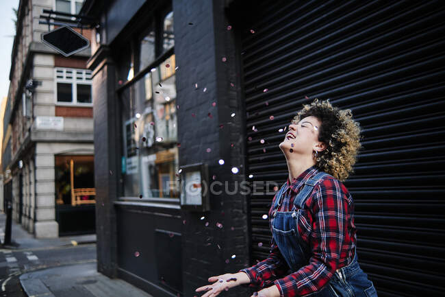 Усміхнена жінка з закритими очима насолоджується конфетті падає перед затвором — стокове фото