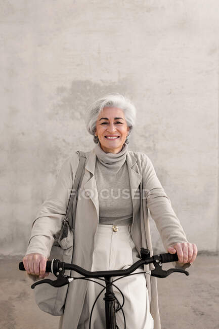 Mulher feliz em casaco de trincheira na bicicleta — Fotografia de Stock